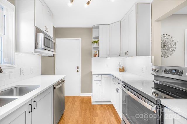 kitchen with white cabinetry, sink, light hardwood / wood-style floors, and appliances with stainless steel finishes