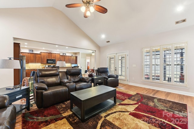 living room featuring ceiling fan, hardwood / wood-style floors, high vaulted ceiling, and french doors