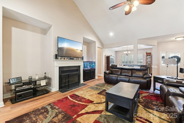 living room with ceiling fan with notable chandelier, wood-type flooring, and high vaulted ceiling