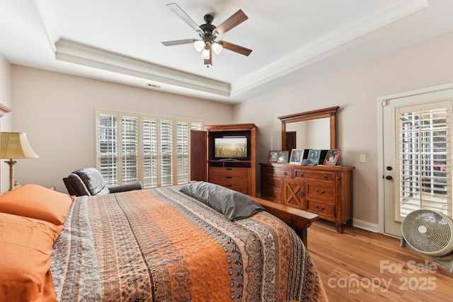 bedroom featuring wood-type flooring, ornamental molding, access to exterior, and a tray ceiling