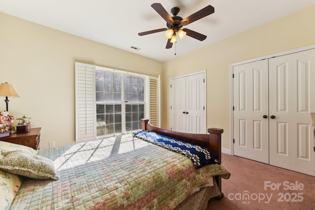 bedroom with ceiling fan, multiple closets, and carpet