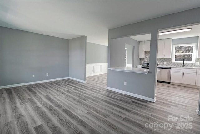 kitchen featuring decorative backsplash, light hardwood / wood-style floors, white cabinetry, and appliances with stainless steel finishes