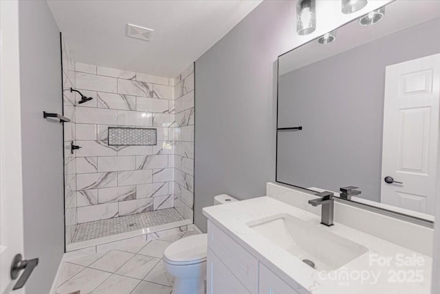 bathroom with toilet, vanity, and tiled shower