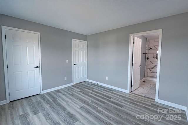 unfurnished bedroom featuring ensuite bath, a closet, and light wood-type flooring