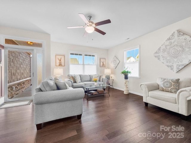 living room featuring ceiling fan, plenty of natural light, and dark wood-type flooring