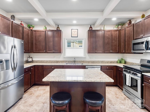 kitchen featuring sink, stainless steel appliances, beamed ceiling, a kitchen bar, and a kitchen island