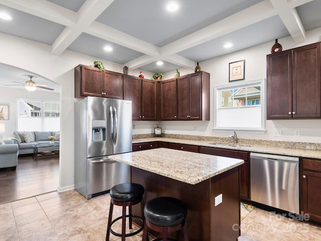 kitchen featuring ceiling fan, sink, stainless steel appliances, a breakfast bar area, and a kitchen island