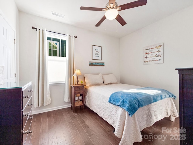 bedroom featuring ceiling fan, dark hardwood / wood-style floors, and multiple windows