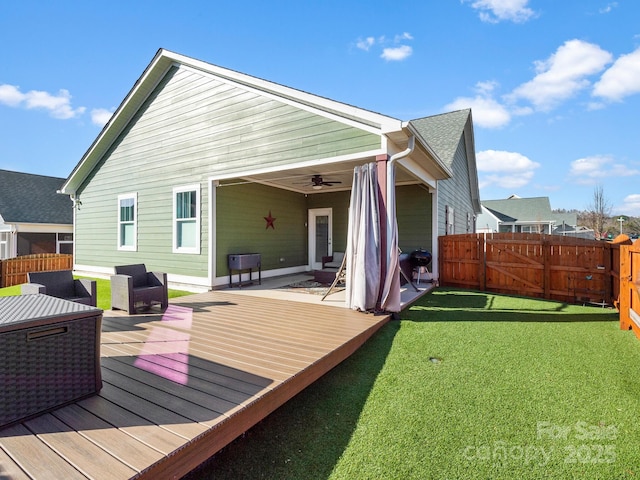 back of house featuring a lawn, ceiling fan, and a deck