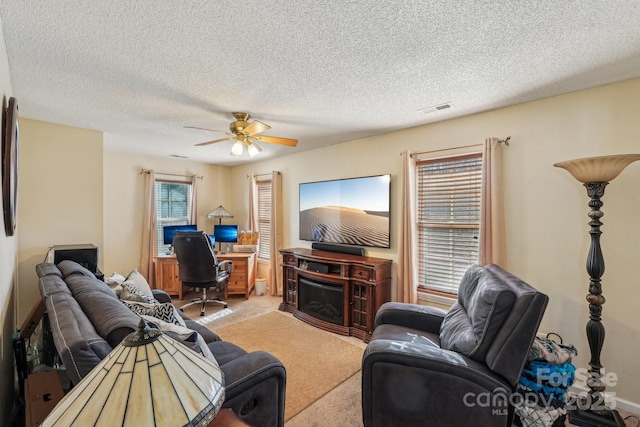 living room featuring a fireplace, a textured ceiling, light colored carpet, and ceiling fan