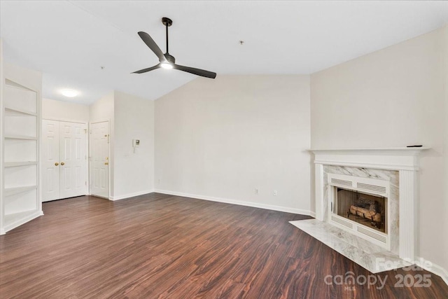 unfurnished living room featuring built in shelves, ceiling fan, dark wood-type flooring, a fireplace, and lofted ceiling