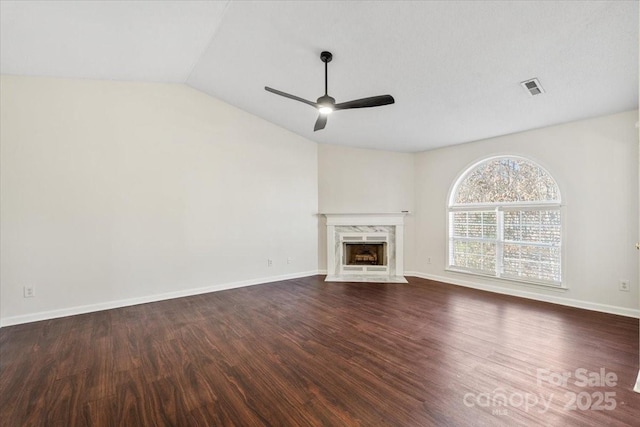 unfurnished living room featuring dark hardwood / wood-style flooring, vaulted ceiling, ceiling fan, and a premium fireplace