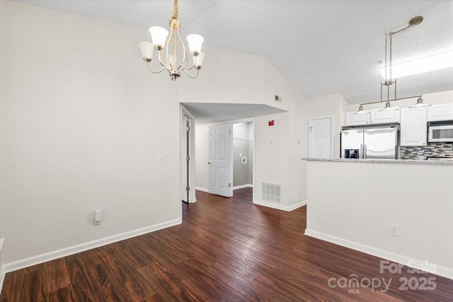 unfurnished living room with a textured ceiling, dark hardwood / wood-style flooring, lofted ceiling, and a notable chandelier