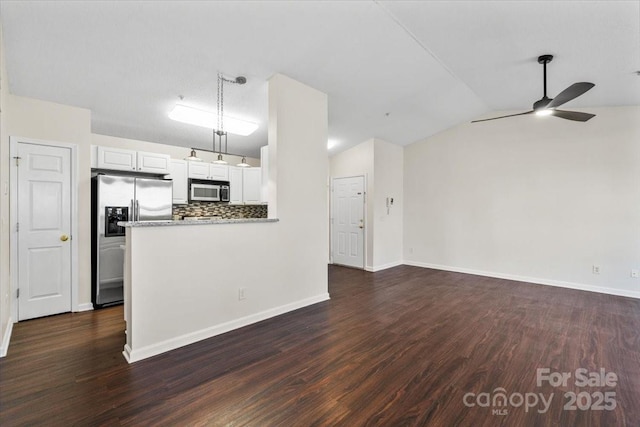 kitchen featuring white cabinetry, kitchen peninsula, stainless steel fridge, vaulted ceiling, and decorative backsplash