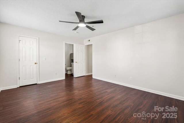 unfurnished bedroom featuring ensuite bath, ceiling fan, and dark wood-type flooring