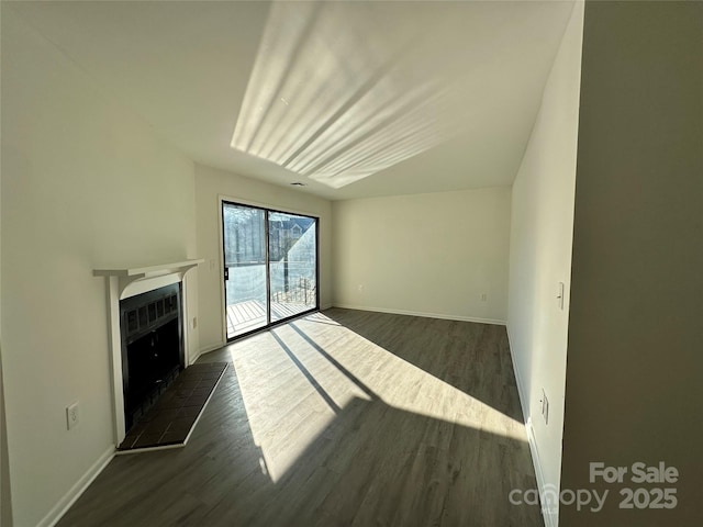 unfurnished living room with a tile fireplace and dark wood-type flooring