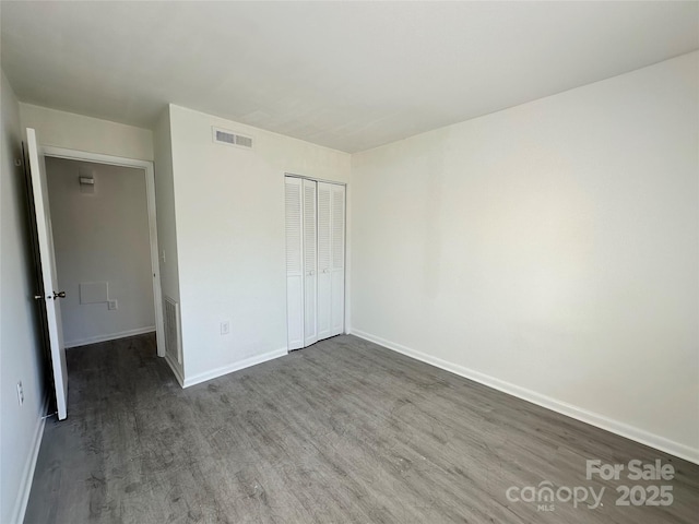 unfurnished bedroom with dark wood-type flooring and a closet