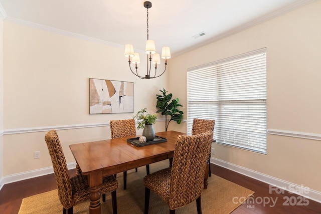 dining space featuring dark wood-type flooring, crown molding, and a notable chandelier