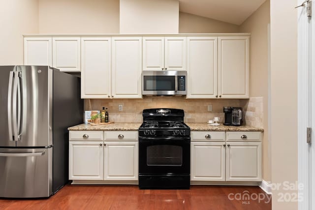 kitchen with backsplash, white cabinets, and stainless steel appliances