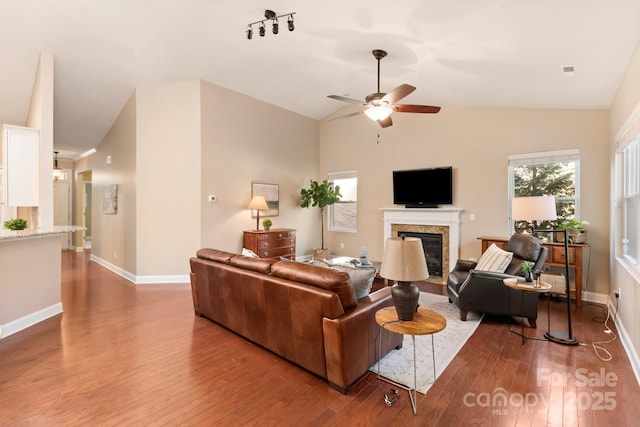 living room featuring ceiling fan, hardwood / wood-style floors, a premium fireplace, and vaulted ceiling