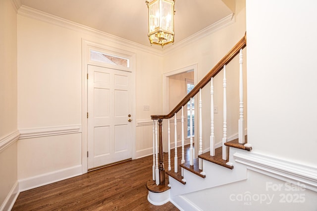 entrance foyer with a healthy amount of sunlight, ornamental molding, dark wood-type flooring, and an inviting chandelier