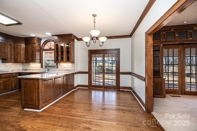 kitchen with kitchen peninsula, an inviting chandelier, light stone counters, and hanging light fixtures