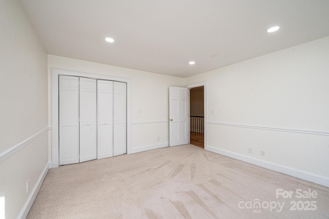 unfurnished bedroom featuring a closet and light colored carpet