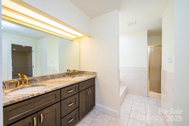 bathroom with tile patterned flooring, vanity, an enclosed shower, and tile walls