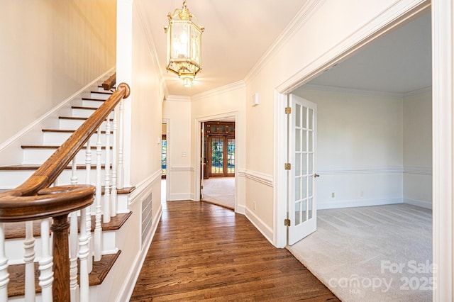 carpeted foyer entrance featuring a chandelier, french doors, and ornamental molding