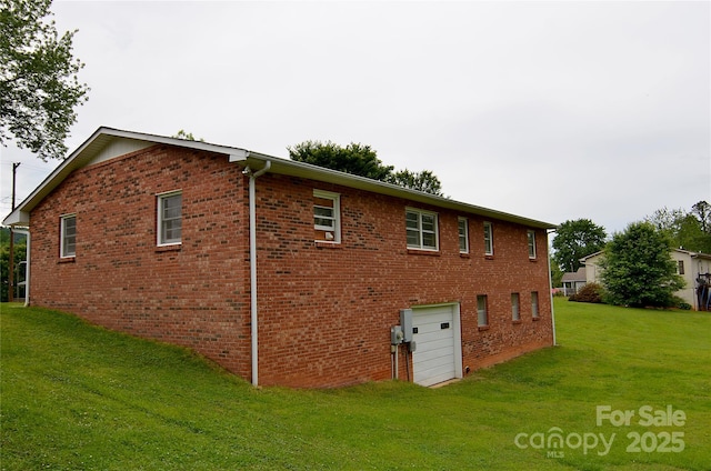 back of property with an attached garage, a lawn, and brick siding