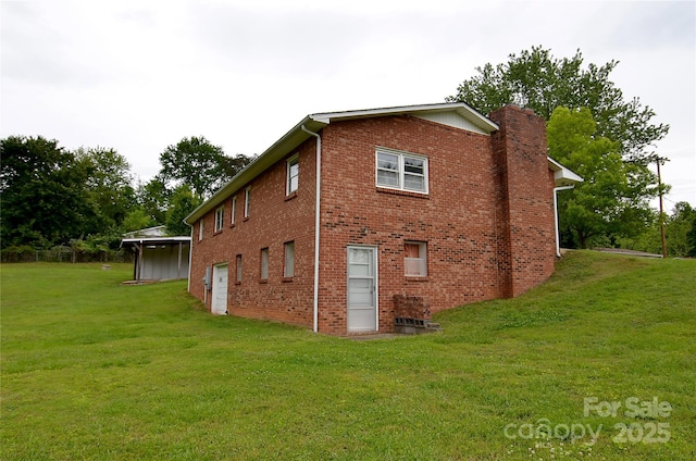 rear view of house with a yard, brick siding, and a chimney