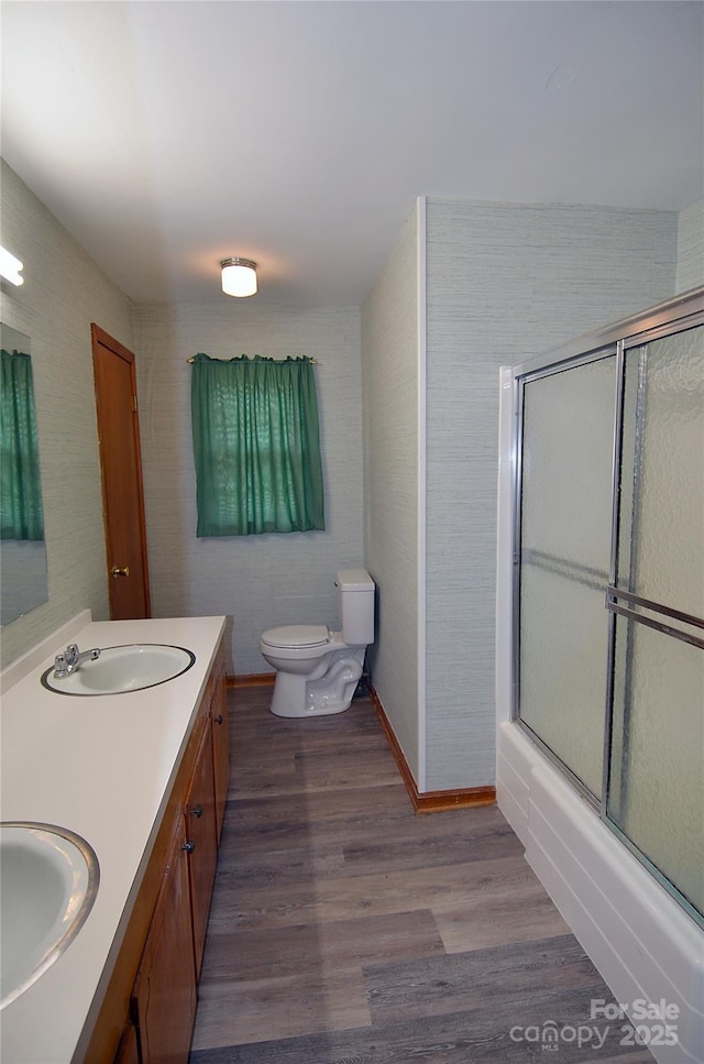 full bathroom with wood finished floors, toilet, double vanity, and combined bath / shower with glass door