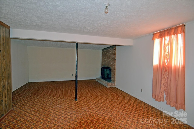 basement featuring a textured ceiling, a fireplace, and carpet floors
