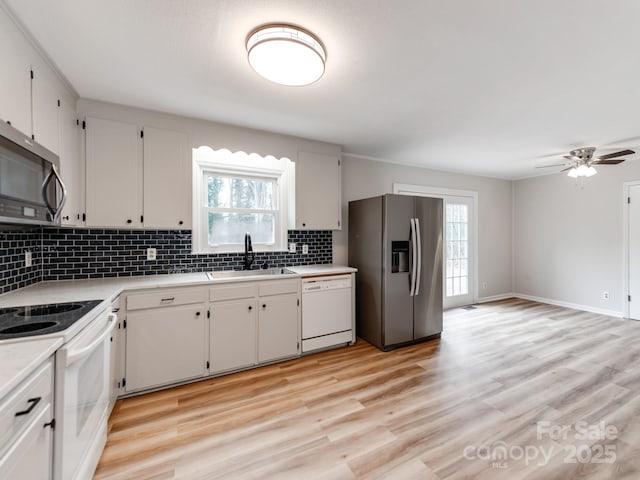 kitchen with appliances with stainless steel finishes, sink, decorative backsplash, and white cabinets