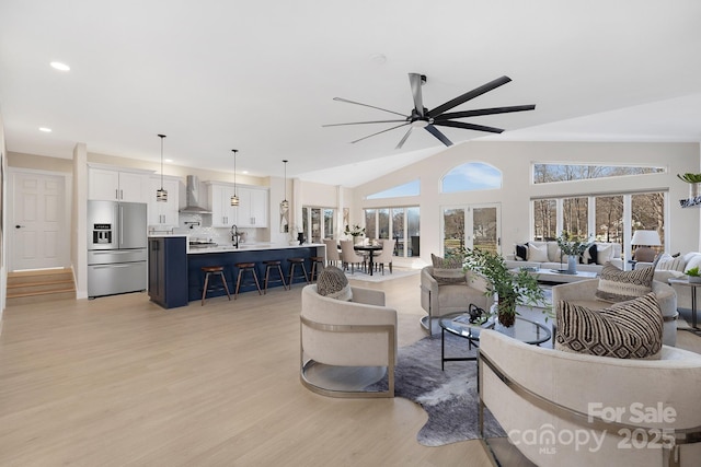 living room featuring ceiling fan, light wood-type flooring, lofted ceiling, and sink