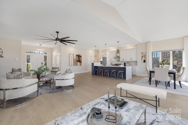 living room with vaulted ceiling, ceiling fan, and light hardwood / wood-style flooring