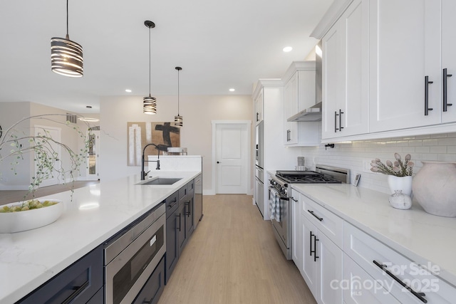 kitchen with sink, appliances with stainless steel finishes, white cabinetry, and hanging light fixtures