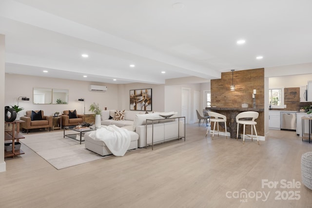 living room with light hardwood / wood-style floors, a wall mounted AC, and beamed ceiling