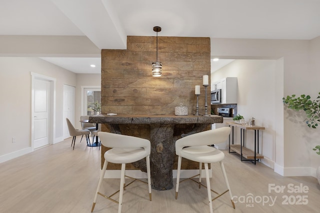 bar with light hardwood / wood-style flooring and decorative light fixtures