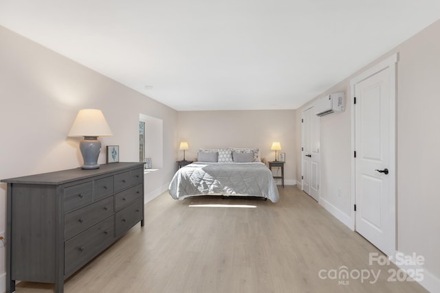 bedroom with light wood-type flooring and a wall unit AC