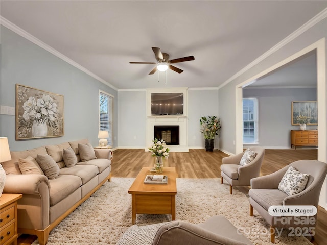 living room featuring wood-type flooring, ceiling fan, and ornamental molding