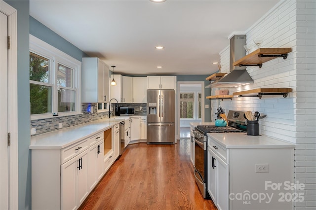 kitchen featuring a wealth of natural light, hanging light fixtures, stainless steel appliances, backsplash, and white cabinetry