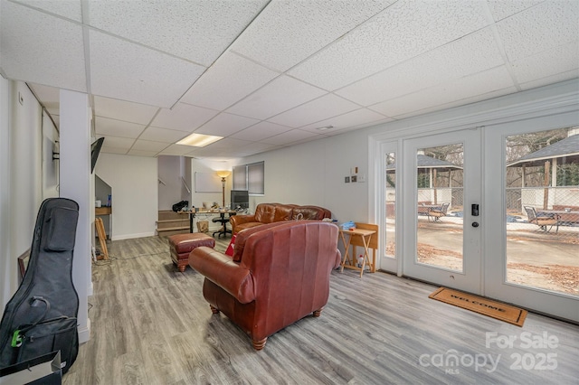 living room featuring wood-type flooring, french doors, and a paneled ceiling