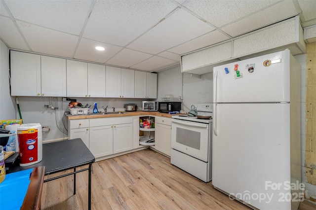 kitchen featuring sink, white cabinetry, white appliances, light hardwood / wood-style floors, and a paneled ceiling