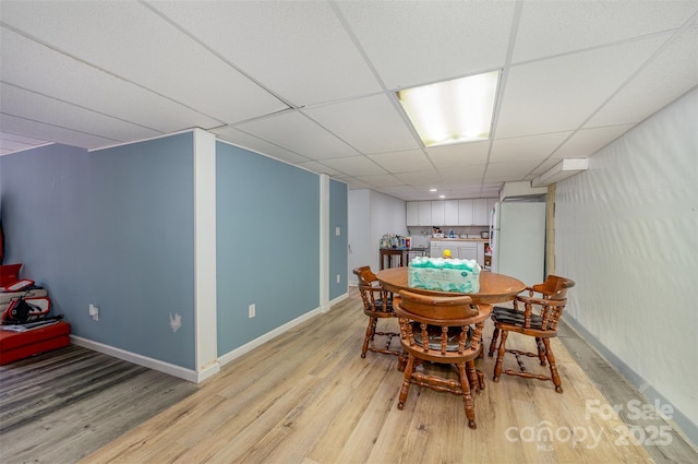 dining space with light wood-type flooring and a drop ceiling