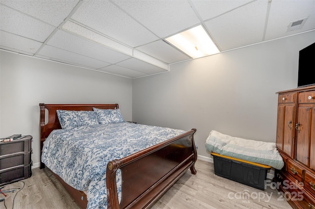 bedroom with light hardwood / wood-style flooring and a drop ceiling