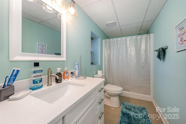 bathroom with a drop ceiling, a shower with curtain, toilet, tile patterned floors, and vanity