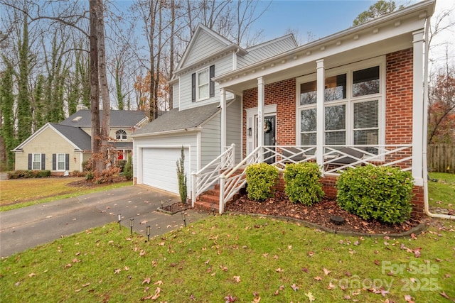 view of front of property with a porch, a front yard, and a garage