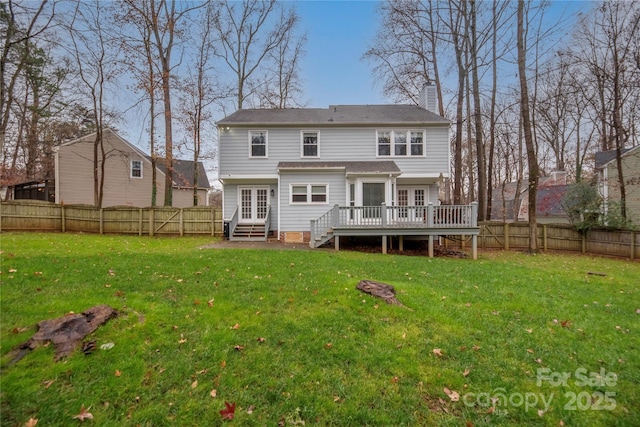 back of property with a lawn, a wooden deck, and french doors