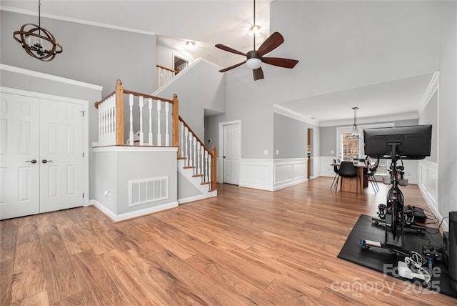 exercise area with ceiling fan with notable chandelier, light wood-type flooring, and ornamental molding